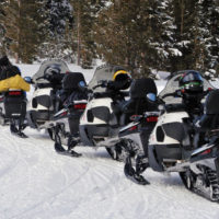 Four snowmobiles sit parked near Fishing Bridge in Yellowstone National Park. Planners say the average snowmobile party in the park has seven sleds. (Ruffin Prevost/Yellowstone Gate - click to enlarge)