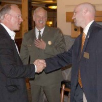 Wyoming Gov. Matt Mead, left, shakes hands with Cody Country Chamber of Commerce Executive Director Scott Balyo as Yellowstone National Park Superintendent Dan Wenk looks on. The men were among those attending a luncheon Friday at Old Faithful Lodge to mark the end of National Travel and Tourism Week and the successulf cooperative effort to plow park roads. (Ruffin Prevost/Yellowstone Gate)