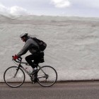 A bicyclist rides past freshly plowed snow along the road between Norris and Canyon Village in this 2012 file photo.