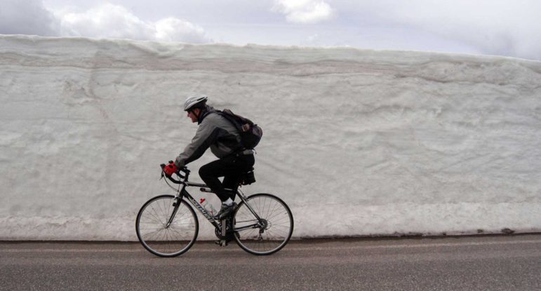 A bicyclist rides past freshly plowed snow along the road between Norris and Canyon Village in this 2012 file photo.