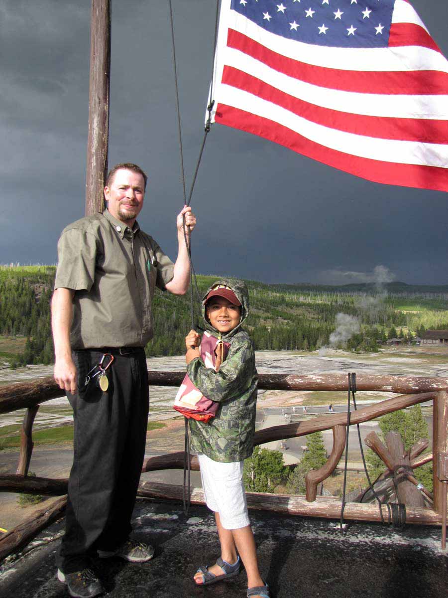 Nathan Bartlett, 8, helps Old Faithful Inn bellman Ed Nabors take down the American flag atop the hotel during a 2012 summer trip to Yellowstone National Park. (NPS photo by Dan Hottle - click to enlarge)