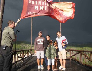 Bellman Ed Nabors displays an Old Faithful Inn flag atop the hotel during a trip to Yellowstone National Park by Nathan Bartlett, 8, center, and his family. (NPS photo by Dan Hottle - click to enlarge)