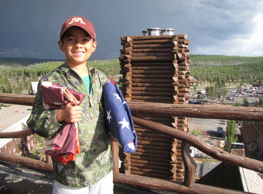 Nathan Bartlett, 8, holds two flags given to him by Xanterra Parks & Resorts atop the Old Faithful Inn in Yellowstone National Park. (NPS photo by Dan Hottle - click to enlarge)