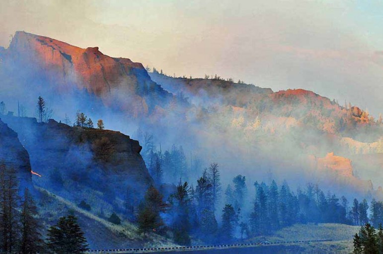 Smoke and sunlight create deep, surreal colors during the 2008 Gunbarrel Fire, which burned along the eastern boundary of Yellowstone National Park.