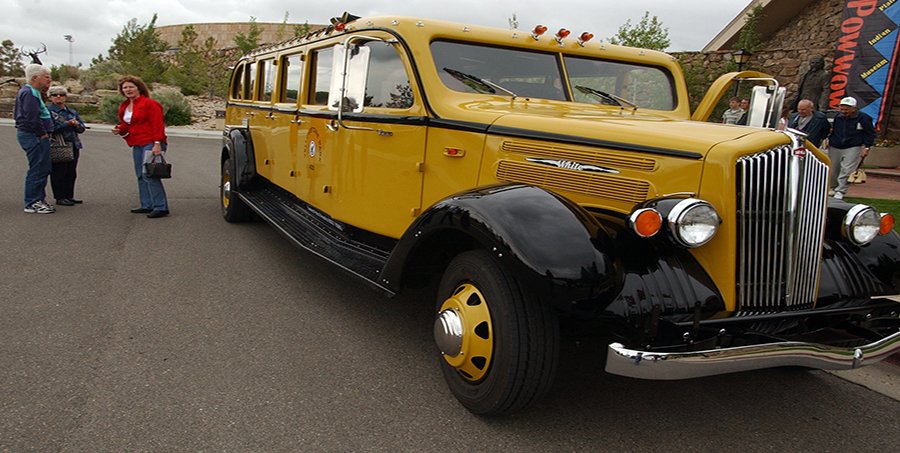 Park County Travel Council Marketing Director Claudia Wade, right, chats with visitors to the Buffalo Bill Historical Center in Cody, Wyo. about a refurbished 1936 tour bus that is used for commercial tours in Yellowstone National Park. (Yellowstone Gate file photo/Ruffin Prevost)