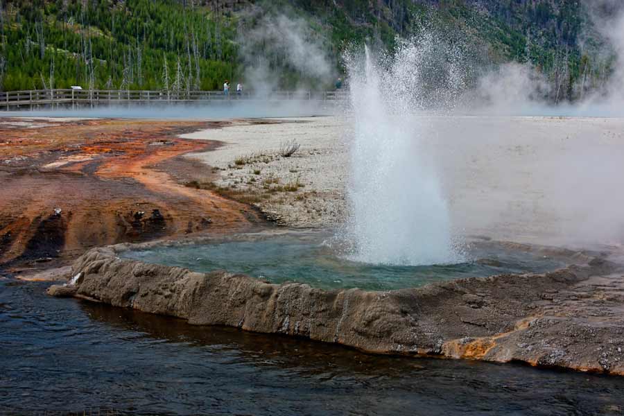 Visitors to Yellowstone National Park walk along a boardwalk near Cliff Geyser in Black Sand Basin. (©Janet White-click to enlarge)