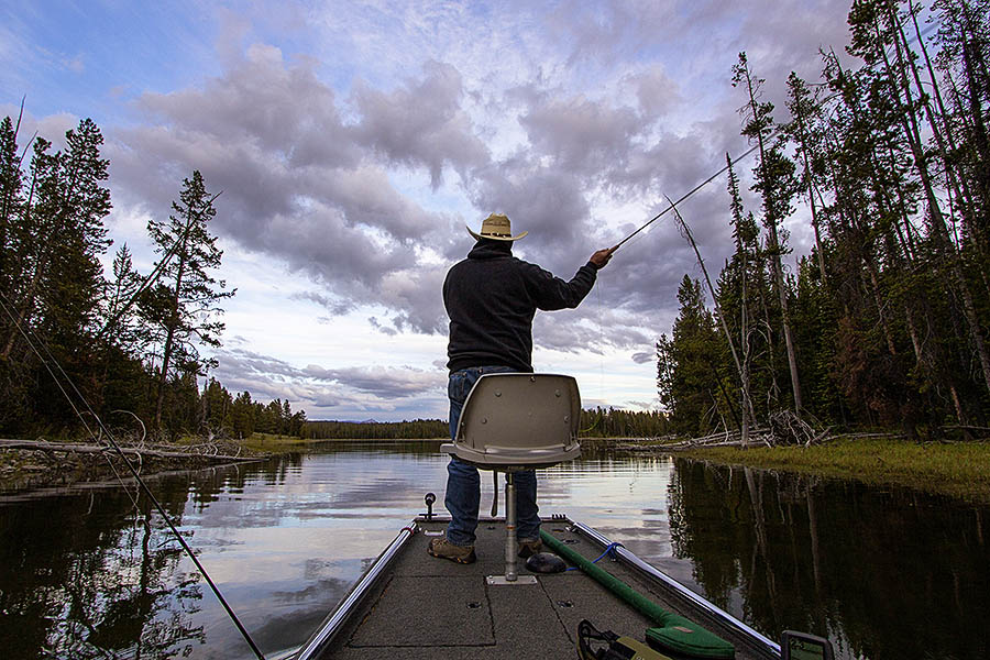 Mike White fly fishes from a boat on a shallow channel in Jackson Lake in Grand Teton National Park. (© Janet White/GeyserWatch.com)