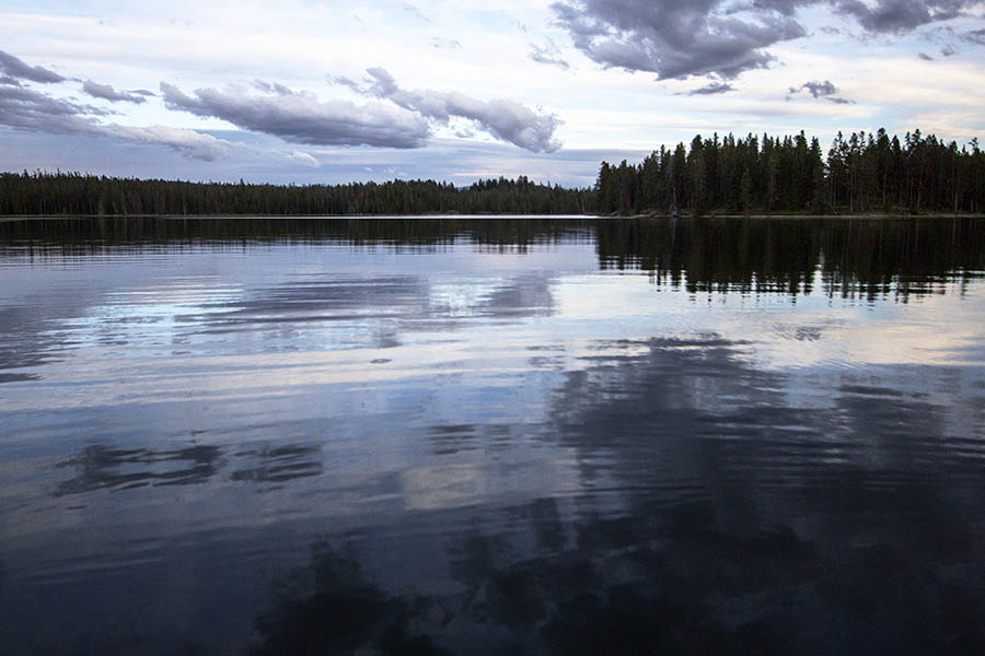 As evening approaches, the calm waters in a cove on Jackson Lake begin to mirror the colors of the sunset in Grand Teton National Park. (© Janet White/GeyserWatch.com)