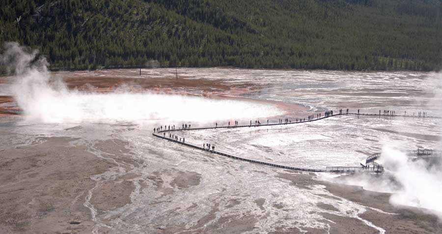 Visitors walk along the boardwalk past Grand Prismatic Spring in the Midway Geyser Basin in Yellowstone National Park. (Ruffin Prevost/Yellowstone Gate)