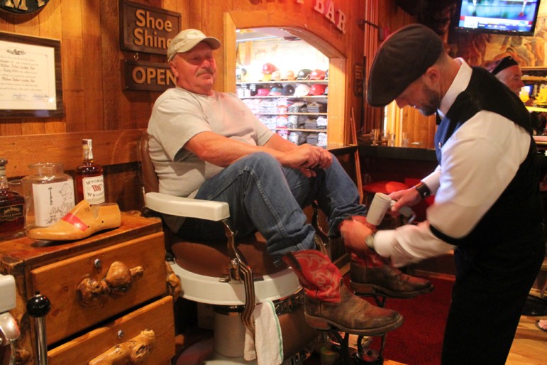 Tim Tetley works on Gordon Little’s boots at Tetley’s shoe-shine stand in the Cowboy Bar in Jackson, Wyo., south of Grand Teton National Park.