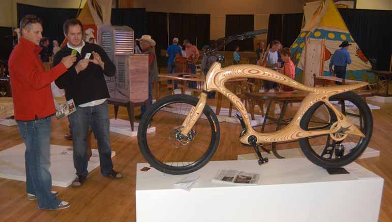 Jake Jones, left, and Dan Neilsen photograph a wooden bicycle created by Powell, Wyo. craftsman Ati Bekes during a visit Saturday to the Cody High Style exhibition in Cody, Wyo.