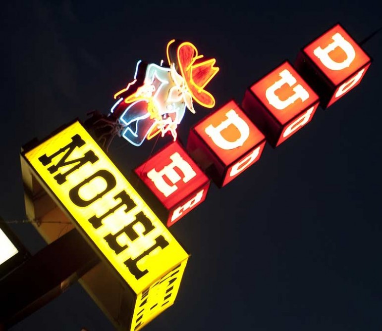 The Dude Motel sign lights up the night sky in West Yellowstone, Mont., where tourism has dropped sharply since the government shutdown closed Yellowstone National Park.