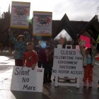 A group of kids hold up protest signs Sunday at the East Gate to Yellowstone National Park.