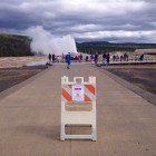 About two dozen visitors to Yellowstone National Park watch Old Faithful Geyser erupt Tuesday afternoon despite a sign advising that the attraction is closed in the wake of a federal goverment shutdown. No visitors were allowed into national parks Tuesday, while those already inside park boundaries will be asked to leave.