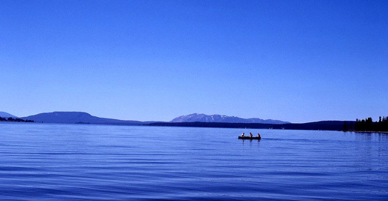 Three people share a canoe on Yellowstone Lake in Yellowstone National Park. 