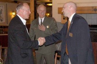 Wyoming Gov. Matt Mead, left, shakes hands with Cody Country Chamber of Commerce Executive Director Scott Balyo as Yellowstone National Park Superintendent Dan Wenk looks on. The men were among those attending a May 2013 luncheon at Old Faithful Lodge to mark the end of National Travel and Tourism Week and the successulf cooperative effort to plow park roads. (Ruffin Prevost/Yellowstone Gate)