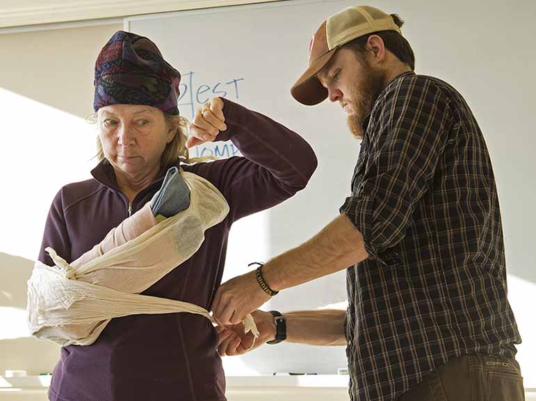 Wilderness Medicine Institute instructor Tate Higgins demonstrates a "sling and swath" on a student.