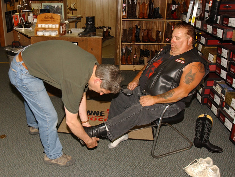 A member of the Hells Angels motorcycle club tries on footwear at Wayne's Boot Shop during the group's 2006 World Run in Cody, Wyo.