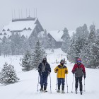 Old Faithful Inn is visible in the background as winter travelers in Yellowstone National Park head out for a trip to Black Sand Pool.