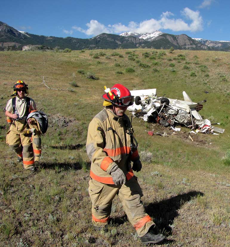 Emergency personnel walk past the wreckage of a crashed airplane Monday after the injured pilot was transported for medical care.