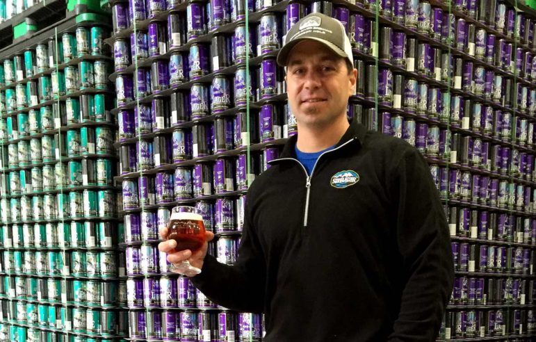 Derek Beardsley samples a Jenny Lake Lager in front of a stack of cans at the Snake River Brewery in Jackson, Wyo.