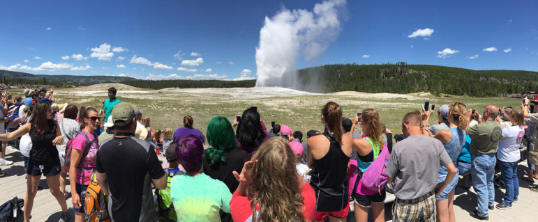 Visitors watch Old Faithful geyser erupt in Yellowstone National Park.