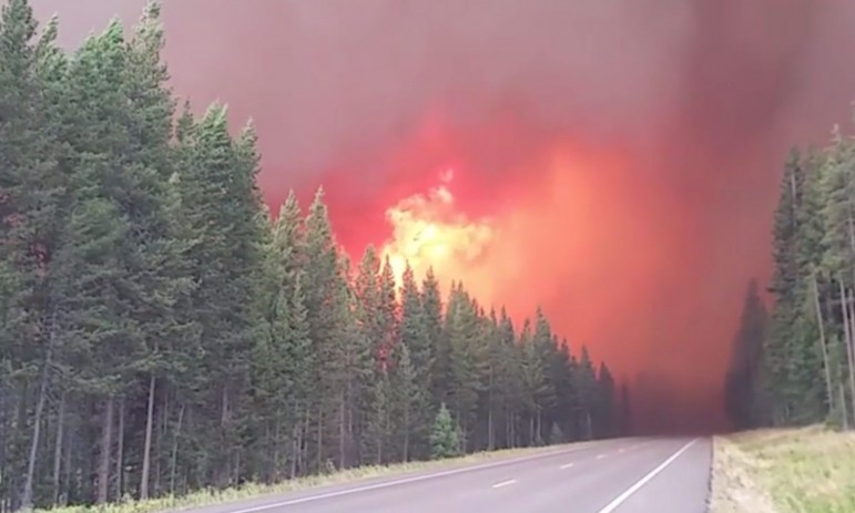 A frame from a video shot Wednesday shows the Berry Fire in Grand Teton National Park burning in heavy timber close to U.S. Highway 89. Officials have closed the road, which connects Grand Teton and Yellowstone National Park, resulting in the closure of Yellowstone’s south entrance, as well as some trails, a campground and a lodge in Grand Teton. The closures may last several days, depending on fire activity, weather and other factors.