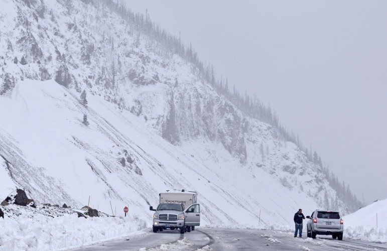Two motorists pause at a pull-out atop Sylvan Pass to discuss snowy road conditions Tuesday in Yellowstone National Park.