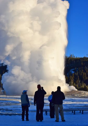 An eruption of Old Faithful draws only a handful of visitors willing to brave frosty early-morning temperatures in Yellowstone National Park.