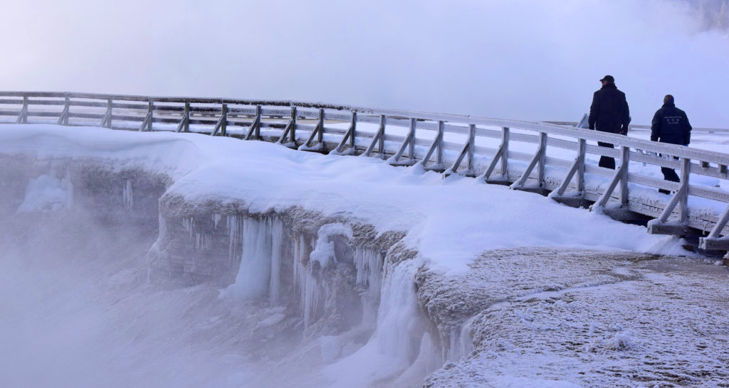 Visitors traverse the snow-covered boardwalk along Excelsior Geyser Crater in Yellowstone National Park. Private businesses have pitched in to keep the park open during the partial government shutdown .